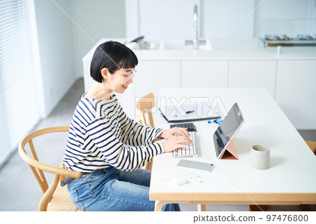 在房間裡的桌子旁工作的年輕女人 在房間裡的桌子旁工作的年輕女人 97476800