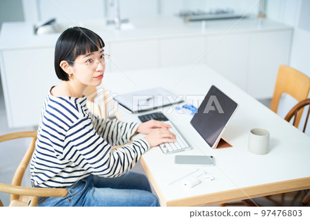 在房間裡的桌子旁工作的年輕女人 在房間裡的桌子旁工作的年輕女人 97476803