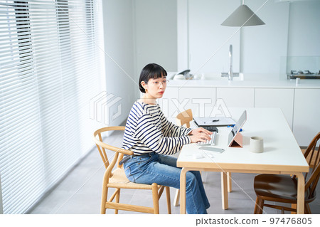 在房間裡的桌子旁工作的年輕女人 97476805