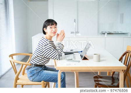 在房間裡的桌子旁工作的年輕女人 在房間裡的桌子旁工作的年輕女人 97476806