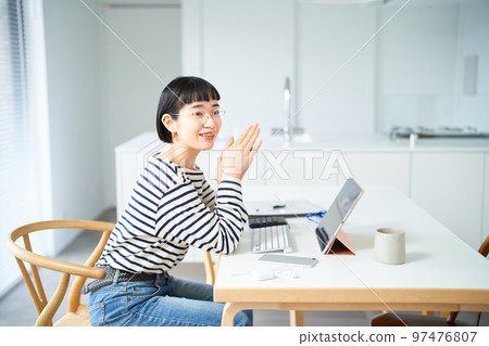 在房間裡的桌子旁工作的年輕女人 在房間裡的桌子旁工作的年輕女人 97476807