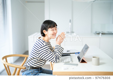 在房間裡的桌子旁工作的年輕女人 在房間裡的桌子旁工作的年輕女人 97476808