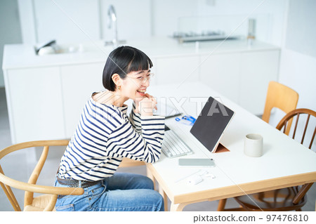 在房間裡的桌子旁工作的年輕女人 在房間裡的桌子旁工作的年輕女人 97476810