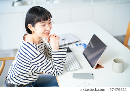 在房間裡的桌子旁工作的年輕女人 在房間裡的桌子旁工作的年輕女人 97476811