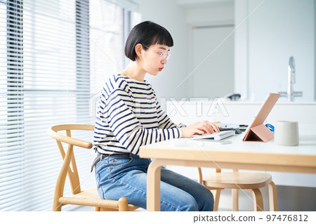在房間裡的桌子旁工作的年輕女人 在房間裡的桌子旁工作的年輕女人 97476812