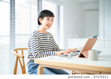 在房間裡的桌子旁工作的年輕女人 在房間裡的桌子旁工作的年輕女人 97476813