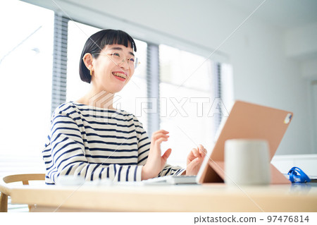 在房間裡的桌子旁工作的年輕女人 在房間裡的桌子旁工作的年輕女人 97476814