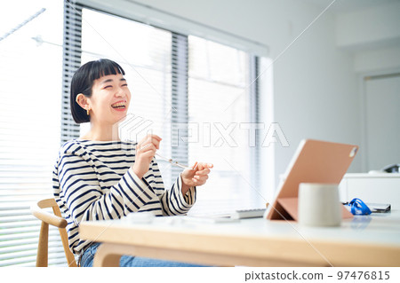 在房間裡的桌子旁工作的年輕女人 在房間裡的桌子旁工作的年輕女人 97476815