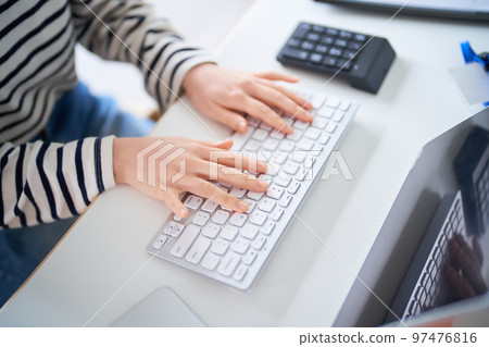 在房間裡的桌子旁工作的年輕女人 在房間裡的桌子旁工作的年輕女人 97476816