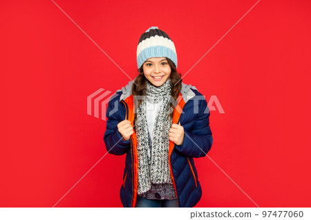 emotional kid with curly hair in puffer jacket and hat. teen girl on red background. emotional kid with curly hair in puffer jacket and hat. teen girl on red background. 97477060