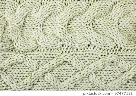 Knitted green background. Large knitted fabric with a pattern. Close-up of a knitted blanket. Horizontal ornament. 97477151