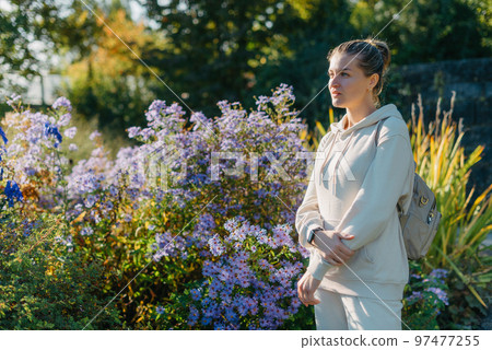 Beautiful elegant woman standing in autumn park with yellow leaves outdoor. Beauty Romantic Girl Outdoors enjoy autumn yellow leaves. Portrait of joyful woman in park during fall. Happy ng nature. Sun 97477255