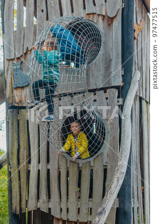 A child climbs up an alpine grid in a park on a playground on a hot summer day. children's playground in a public park, entertainment and recreation for children, mountaineering training. Child A child climbs up an alpine grid in a park on a playground on a hot summer day. children's playground in a public park, entertainment and recreation for children, mountaineering training. Child 97477515