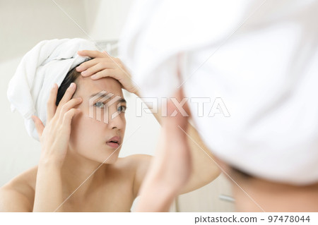 Problem skin. Concerned young asian women popping pimple on cheek while standing near mirror in bathroom. young asian women with acne Problem skin. Concerned young asian women popping pimple on cheek while standing near mirror in bathroom. young asian women with acne 97478044