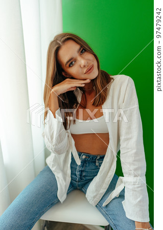 Portrait of attractive lovely girl wearing crop top and shirt posing over green studio background Portrait of attractive lovely girl wearing crop top and shirt posing over green studio background 97479242