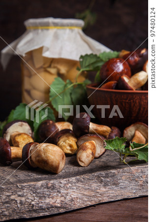 Pile of Imleria Badia or Boletus badius mushrooms commonly known as the bay bolete with canned mushroom in glass jar on vintage wooden background.. Pile of Imleria Badia or Boletus badius mushrooms commonly known as the bay bolete with canned mushroom in glass jar on vintage wooden background.. 97480124