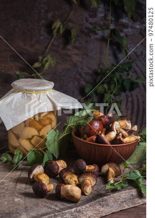 Pile of Imleria Badia or Boletus badius mushrooms commonly known as the bay bolete with canned mushroom in glass jar on vintage wooden background.. Pile of Imleria Badia or Boletus badius mushrooms commonly known as the bay bolete with canned mushroom in glass jar on vintage wooden background.. 97480125