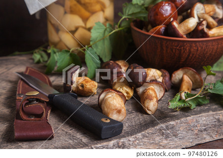 Pile of Imleria Badia or Boletus badius mushrooms commonly known as the bay bolete with canned mushroom in glass jar and knife on vintage wooden background.. Pile of Imleria Badia or Boletus badius mushrooms commonly known as the bay bolete with canned mushroom in glass jar and knife on vintage wooden background.. 97480126