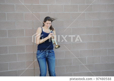 Female trumpet player blowing her horn outside. 97480588