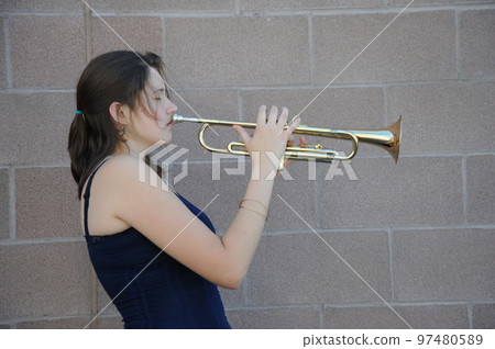 Female trumpet player blowing her horn outside. 97480589