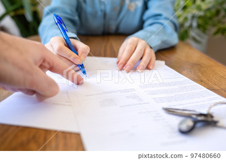 The employee points his finger at the contract where you need to sign it. Hands close-up. The keys are on the table. Rental and purchase of real estate The employee points his finger at the contract where you need to sign it. Hands close-up. The keys are on the table. Rental and purchase of real estate 97480660