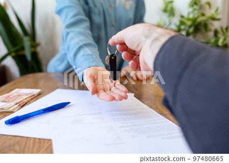 Realtor gives the keys to the new owner. Close-up of hands. Indoor. Rental and purchase Realtor gives the keys to the new owner. Close-up of hands. Indoor. Rental and purchase 97480665