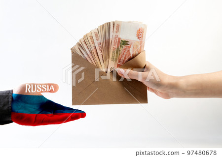 Illegal salary. A woman's hand gives an envelope of money to a man's hand in a shirt, with the palm painted in the flag of Russia. White background. The concept of the world anti-corruption day Illegal salary. A woman's hand gives an envelope of money to a man's hand in a shirt, with the palm painted in the flag of Russia. White background. The concept of the world anti-corruption day 97480678