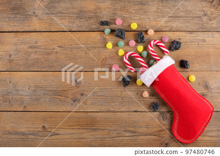 Red Epiphany Befana's stocking with sweet coal and candy on rustic wooden background, Italian Epiphany day tradition Red Epiphany Befana's stocking with sweet coal and candy on rustic wooden background, Italian Epiphany day tradition 97480746