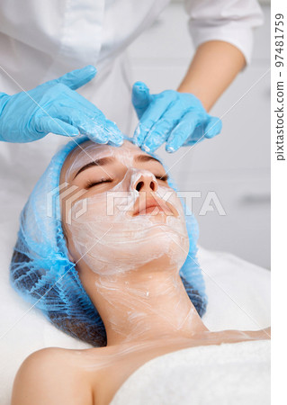 beautician applies the mask to the face of beautiful woman 97481759