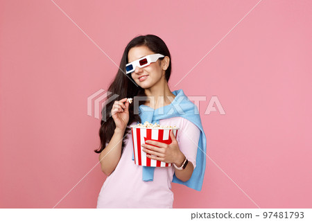 woman watching movie film, holding bucket of popcorn 97481793