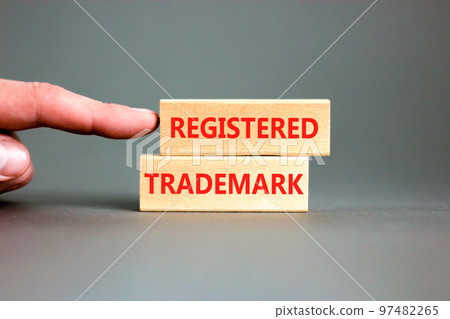 Registered trademark symbol. Concept word Registered trademark on wooden blocks. Beautiful grey table grey background. Businessman hand. Business and registered trademark concept. Copy space. 97482265