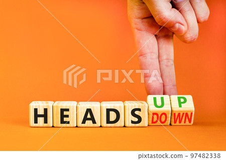 Heads up or down symbol. Concept words Heads up Heads down wooden cubes. Businessman hand. Beautiful orange table orange background. Business heads up or down concept. Copy space. Heads up or down symbol. Concept words Heads up Heads down wooden cubes. Businessman hand. Beautiful orange table orange background. Business heads up or down concept. Copy space. 97482338