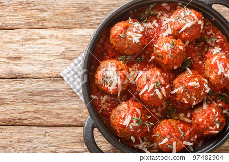 Fried meatballs with parmesan and then stewed in spicy tomato sauce close-up in a frying pan. Horizontal top view Fried meatballs with parmesan and then stewed in spicy tomato sauce close-up in a frying pan. Horizontal top view 97482904
