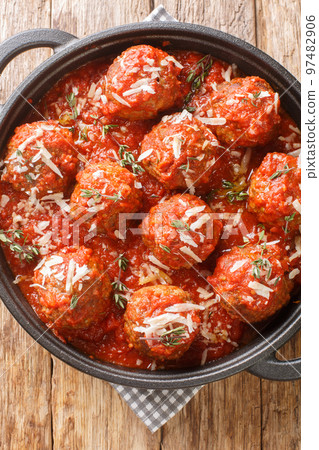 Polpette al Sugo juicy Italian meatballs in a rich tomato sauce closeup on the pan. Vertical top view 97482906