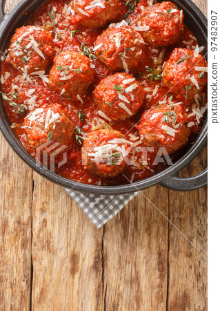 Italian meatballs with parmesan in spicy tomato sauce close-up in a frying pan. Vertical top view 97482907