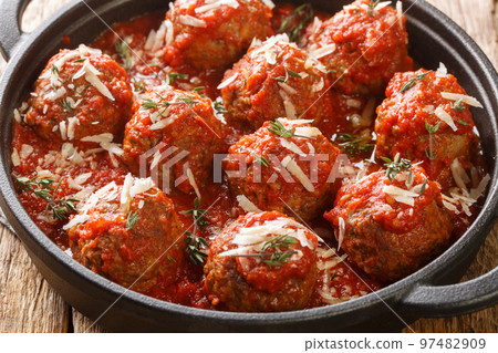 Fried meatballs with parmesan and then stewed in spicy tomato sauce close-up in a frying pan. Horizontal 97482909