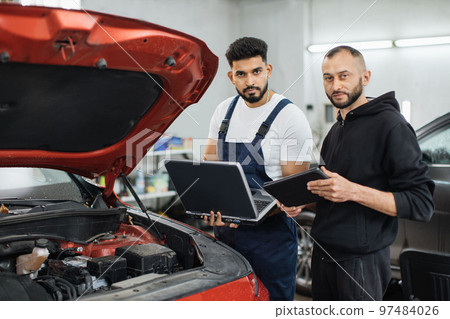 Serious focused men car technician mechanics repairing car problem of engine Serious focused men car technician mechanics repairing car problem of engine 97484026