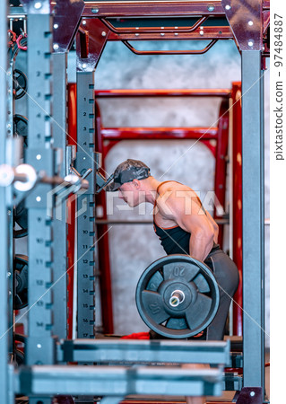 young athlete lifts barbell in gym 97484887