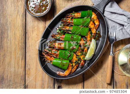 Spicy garlic tiger Prawns Shrimps on frying pan with lemon leaves on wooden background, top view 97485304