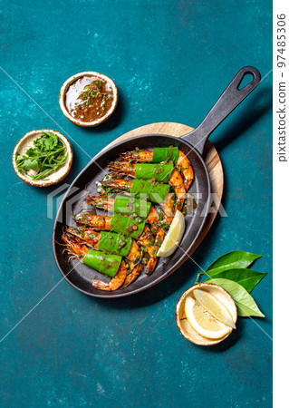 Spicy garlic tiger Prawns Shrimps on frying pan with lemon leaves on blue bakground, top view 97485306