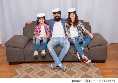 virtual reality family. happy parents with kid girl use modern technology on sofa. 97485674