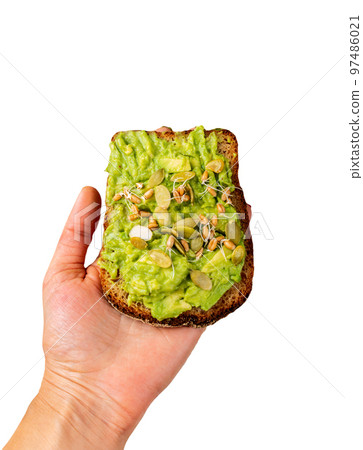 Avocado Guacamole Sandwich in a female hand with pumpkin seeds and wheat seedlings isolated background Avocado Guacamole Sandwich in a female hand with pumpkin seeds and wheat seedlings isolated background 97486021
