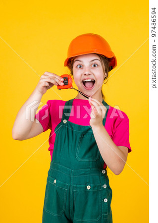 cheerful child laborer using building uniform and tape measure tool, sizing cheerful child laborer using building uniform and tape measure tool, sizing 97486594