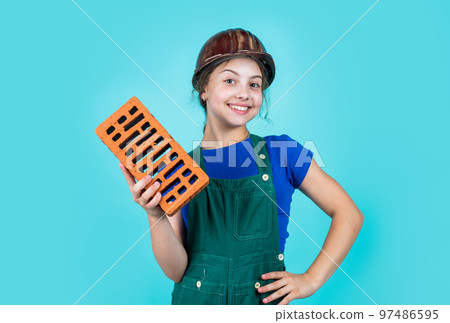 International workers day. girl in helmet plays builder with brick. building a house. Kid build construction. engineer teen is construction worker. Professional craftsman or workman 97486595