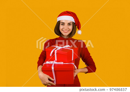 Happy excited young woman in santa hat with gift boxes 97486837