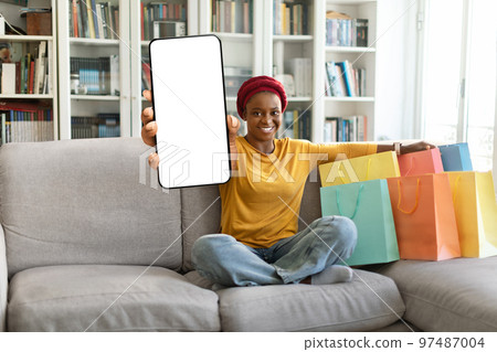 Happy black woman shopaholic showing phone with blank screen 97487004