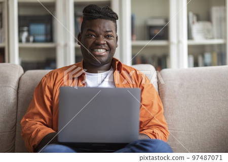 Positive african american man freelancer working from home, using laptop Positive african american man freelancer working from home, using laptop 97487071