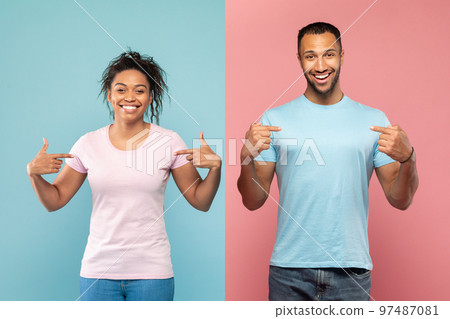 Happy african american man and woman in empty t-shirts pointing fingers at themselves, pink and blue background 97487081