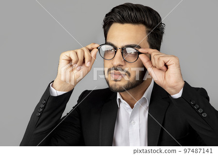 Portrait Of Handsome Young Arab Businessman Wearing Suit And Eyeglasses Looking Away Portrait Of Handsome Young Arab Businessman Wearing Suit And Eyeglasses Looking Away 97487141