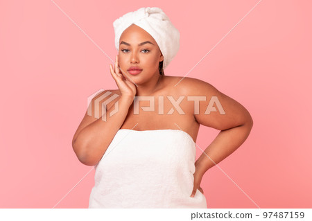 Portrait of beautiful plus size black woman wrapped in bath towel, good-looking lady with smooth skin, pink background Portrait of beautiful plus size black woman wrapped in bath towel, good-looking lady with smooth skin, pink background 97487159